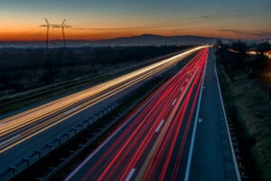 Photo of an Italian road at night with light trails and mountains in the background