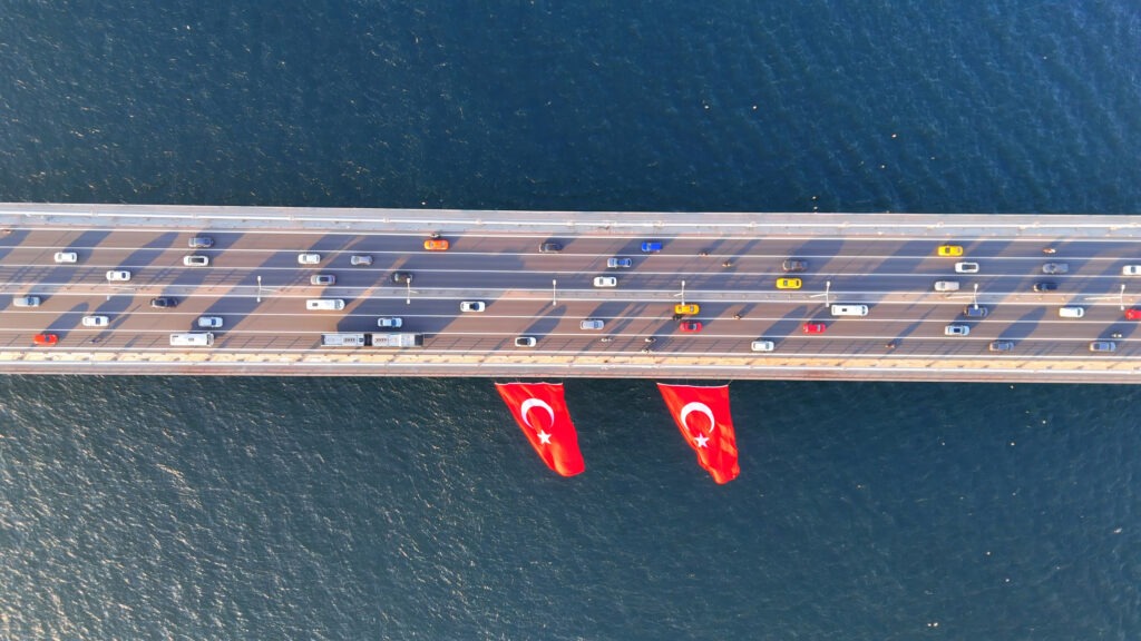 Martyrs Bridge in Istanbul, Turkey with two flags and traffic.