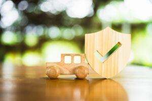 Wooden car with protective shield o protect from accident and damage, Auto Insurance symbol.