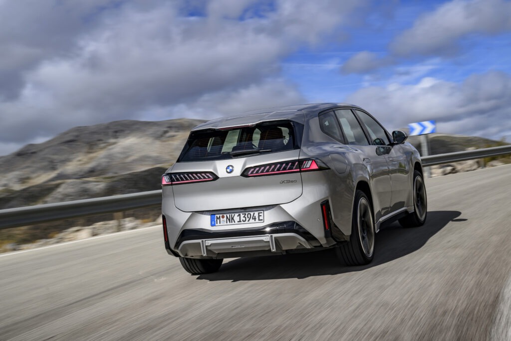 Rückansicht des BMW iX3 beim Fahren auf einer Straße