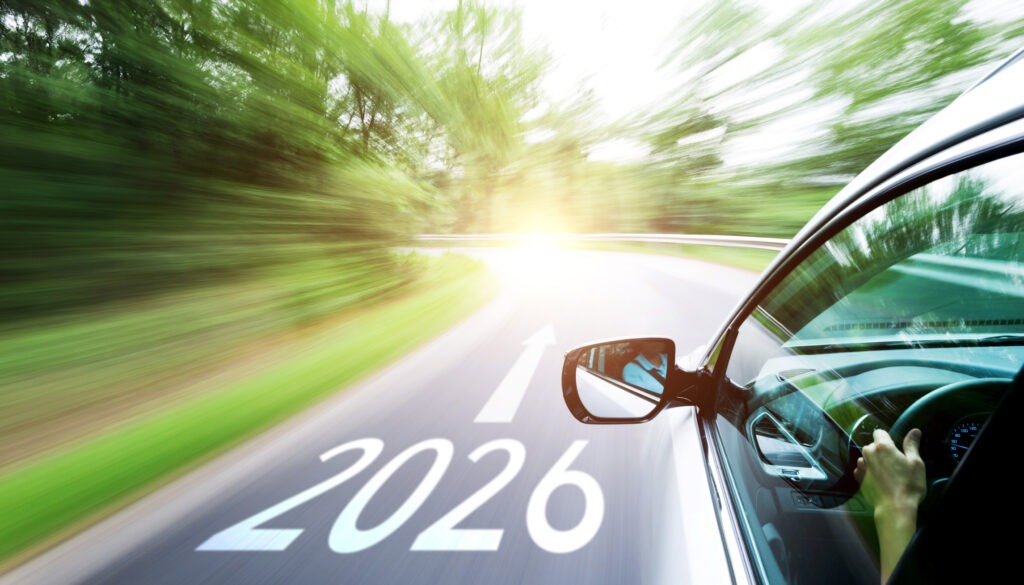 Man hand driving car through the forest, with new number 2026 and arrow sign on the road