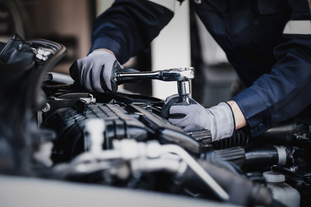 Professioneller Mechaniker, der in der Garage am Motor des Autos arbeitet. Autoreparaturservice. Das Konzept, die Bereitschaft des Autos vor der Abfahrt zu überprüfen.