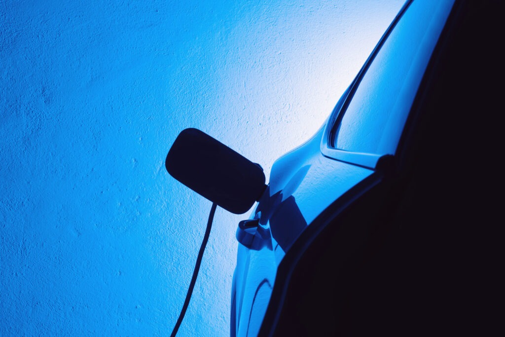 An electric car to charge in a private parking with the scene lit dramatically in blue tones.