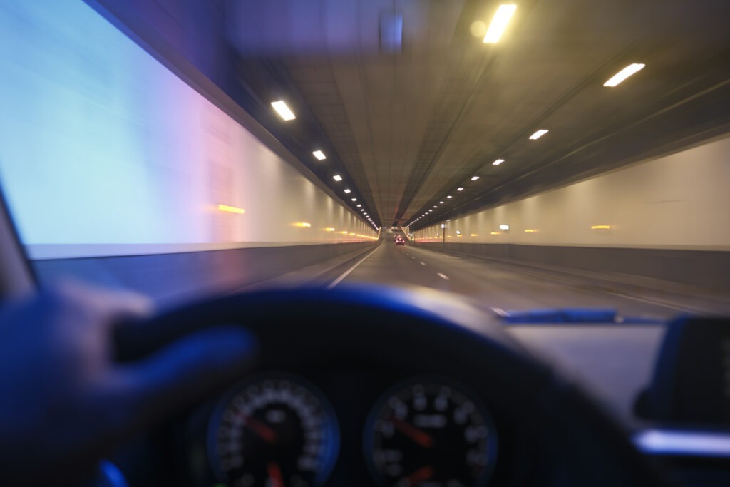 Verschwommene Sicht aus dem Inneren eines fahrenden Autos, das durch einen hell erleuchteten Tunnel fährt