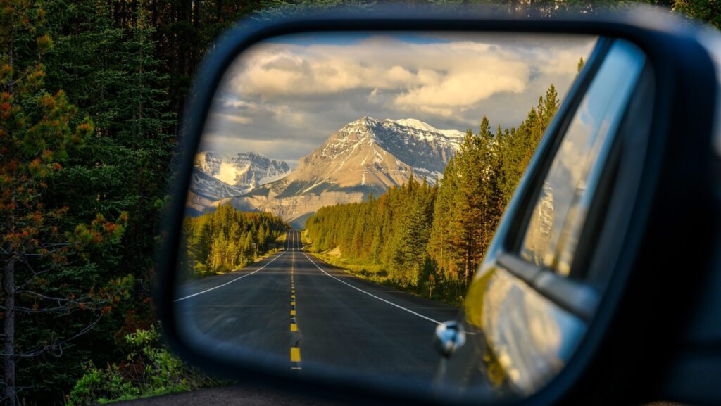 Fahren Sie durch eine Bergstraße und beobachten Sie die wunderschöne Landschaft im Rückspiegel auf dem Icefields Parkway in der Nähe von Jasper